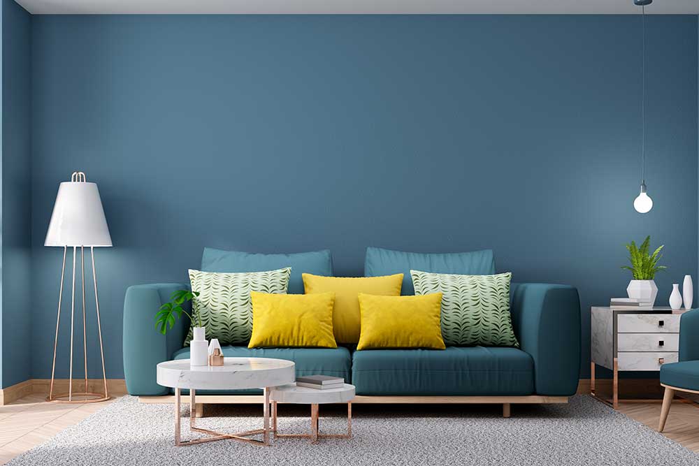 blaues Sofa vor blauer Wand- Wohnzimmer gestaltung